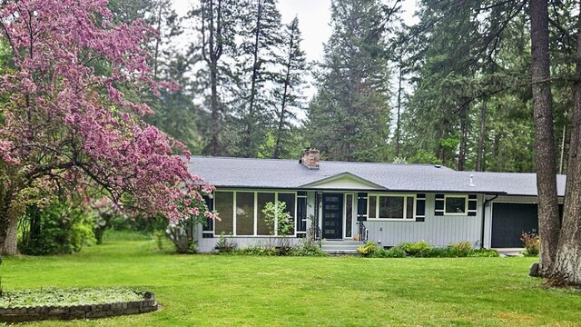 1103 Greers Ferry Rd, Libby, MT 59923 - ranch-style home featuring a front lawn, a sunroom, a chimney, and roof with shingles
