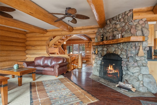 living room with beamed ceiling, stairs, a fireplace, rustic walls, and wood-type flooring