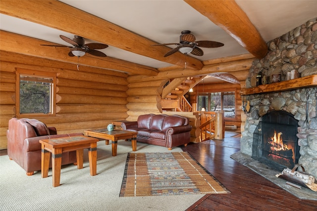 living room featuring stairway, beam ceiling, a fireplace, rustic walls, and wood-type flooring