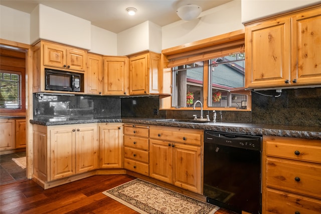 kitchen with black appliances, a sink, backsplash, dark wood-style floors, and dark stone counters