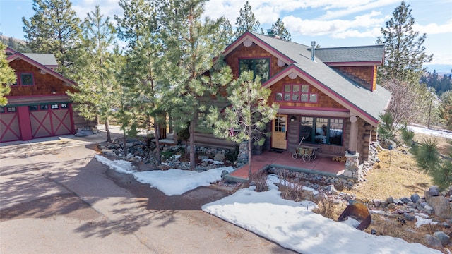 view of front facade with driveway, a shingled roof, and a garage