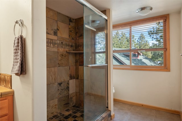 bathroom featuring tile patterned floors, baseboards, vanity, and a shower stall