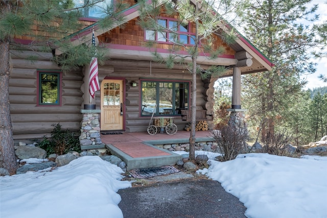 entrance to property with a porch and log siding