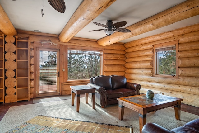 sitting room featuring log walls, beam ceiling, wood finished floors, and a ceiling fan