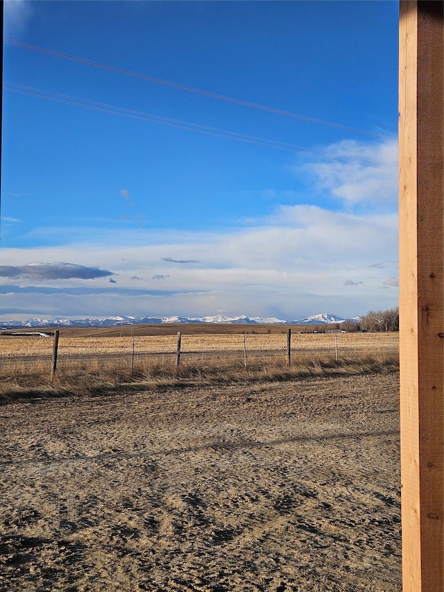 view of yard featuring a mountain view, a rural view, and fence