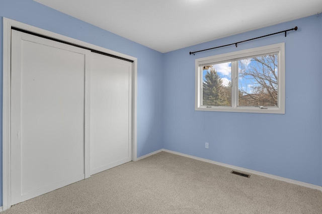 unfurnished bedroom with carpet flooring, baseboards, visible vents, and a closet