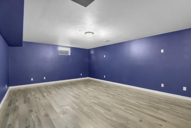 empty room with wood finished floors, baseboards, and a textured ceiling