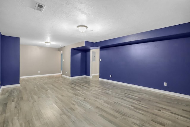 spare room with visible vents, baseboards, a textured ceiling, and wood finished floors