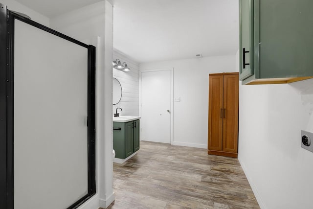 full bathroom featuring a stall shower, vanity, baseboards, and wood finished floors