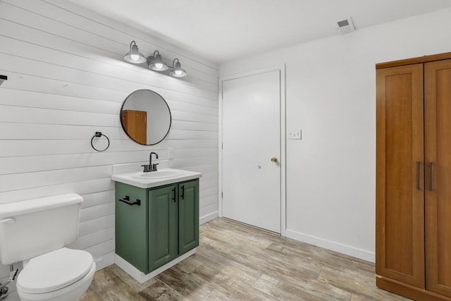 bathroom featuring vanity, wood finished floors, visible vents, baseboards, and toilet