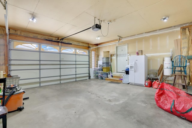 garage featuring white refrigerator with ice dispenser and a garage door opener