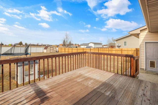 deck with a yard, an outdoor structure, a storage shed, and a trampoline