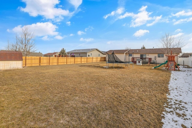 view of yard featuring an outbuilding, a trampoline, fence, a playground, and a storage shed