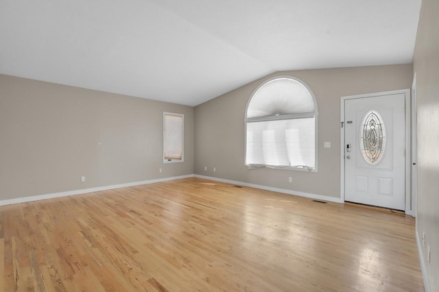 foyer entrance featuring light wood finished floors, visible vents, baseboards, and vaulted ceiling