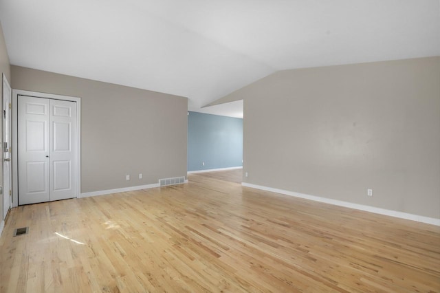 spare room with visible vents, baseboards, light wood-style floors, and vaulted ceiling