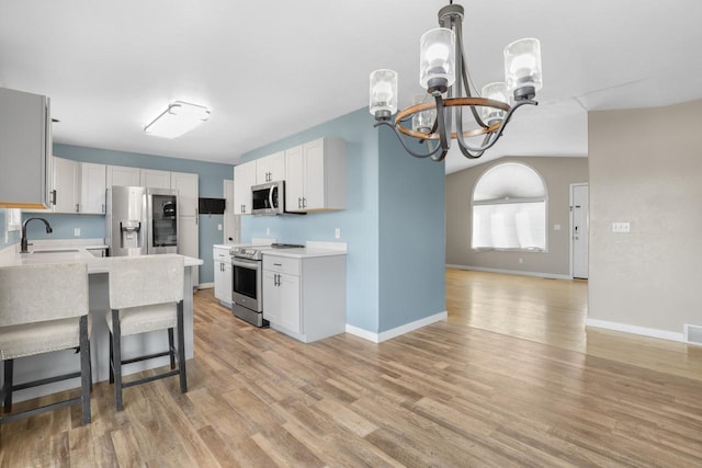 kitchen featuring light wood finished floors, appliances with stainless steel finishes, light countertops, and a sink