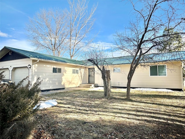 rear view of house featuring metal roof and a garage