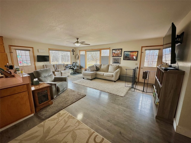 living area with dark wood-style floors, a textured ceiling, and ceiling fan