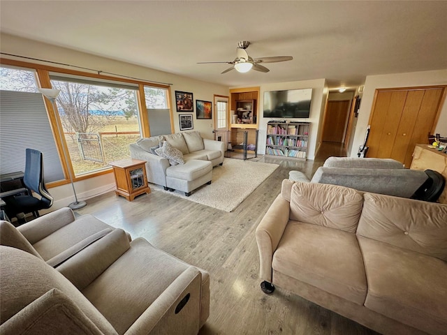 living room with ceiling fan, baseboards, and wood finished floors