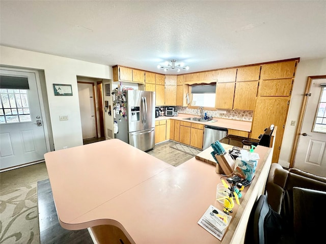 kitchen with light countertops, decorative backsplash, appliances with stainless steel finishes, a textured ceiling, and a sink