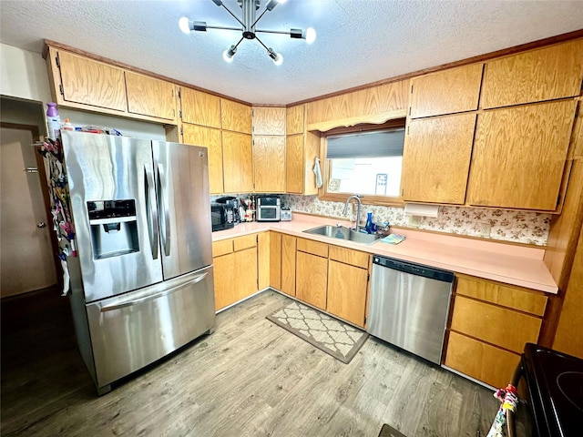 kitchen with light wood finished floors, black appliances, light countertops, and a sink