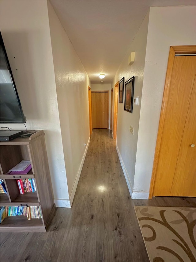 hallway with baseboards and wood finished floors