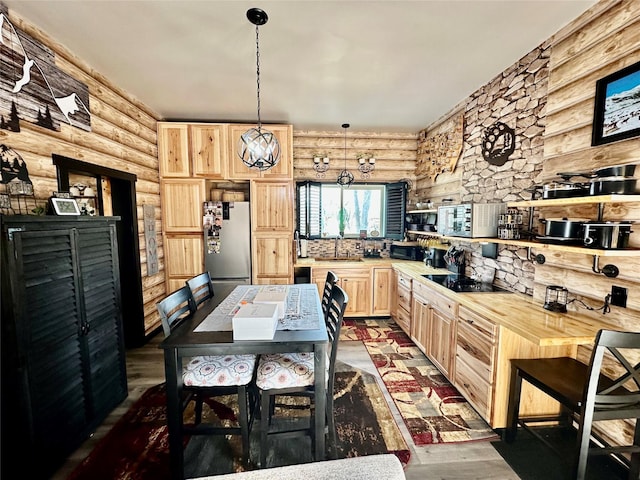 kitchen with light brown cabinetry, freestanding refrigerator, dark wood-style floors, black electric cooktop, and a sink