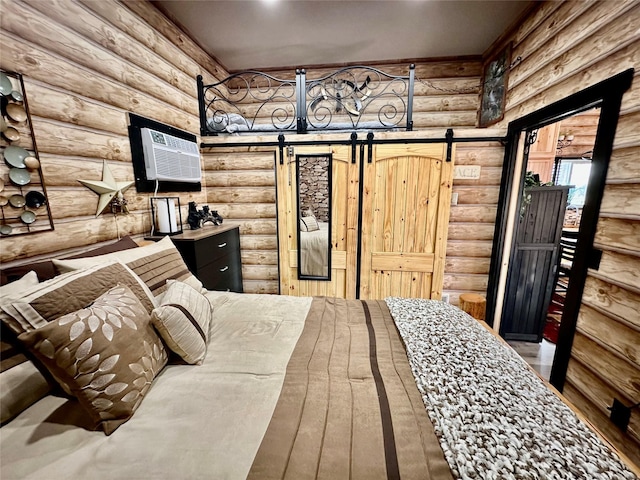 bedroom featuring a wall mounted air conditioner, a barn door, and wood finished floors