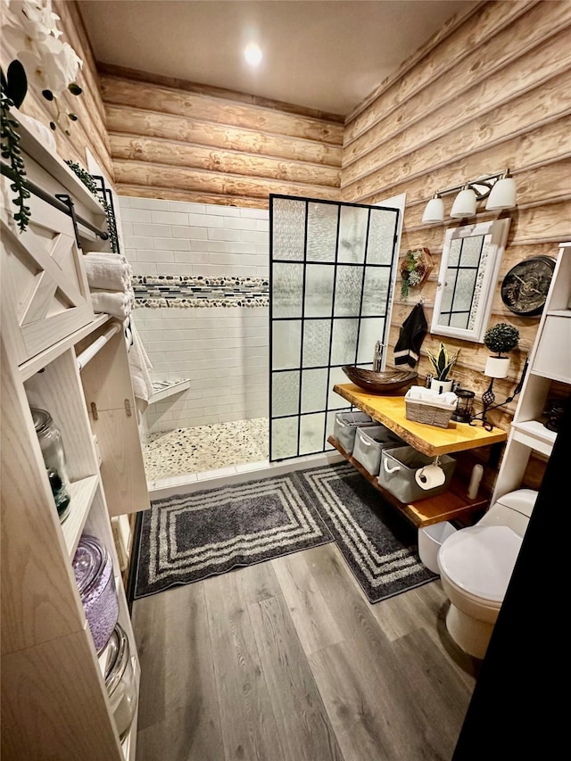 full bathroom featuring vanity, wood finished floors, walk in shower, toilet, and rustic walls