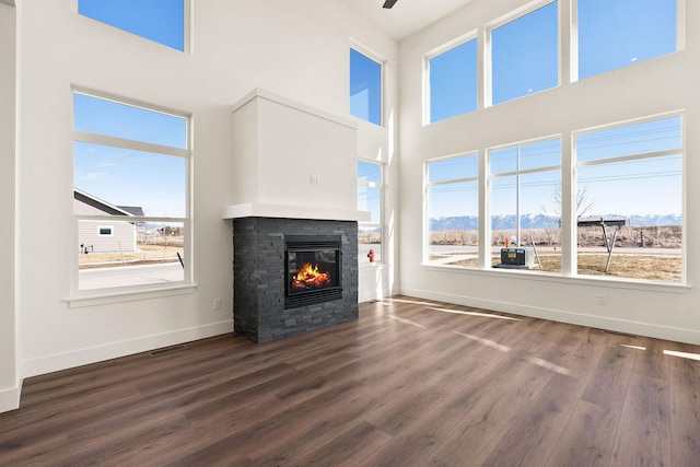 unfurnished living room featuring a healthy amount of sunlight, a fireplace, and dark wood-style flooring