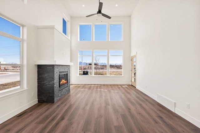 590 Stillwater Rd, Kalispell, MT 59901 - unfurnished living room with a ceiling fan, a stone fireplace, wood finished floors, and a towering ceiling