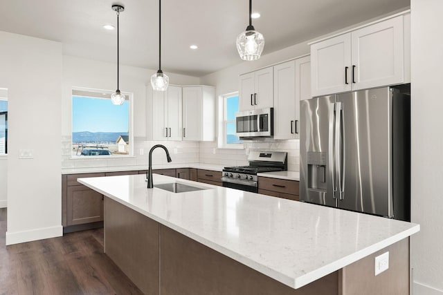 kitchen featuring tasteful backsplash, a sink, light stone countertops, stainless steel appliances, and dark wood-style flooring