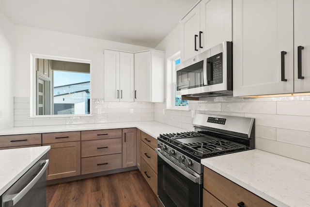 kitchen with light stone counters, stainless steel appliances, tasteful backsplash, and dark wood-style flooring