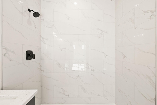 full bath featuring a tile shower and vanity