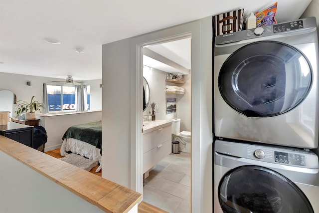 laundry room featuring laundry area, stacked washer and dryer, and a ceiling fan