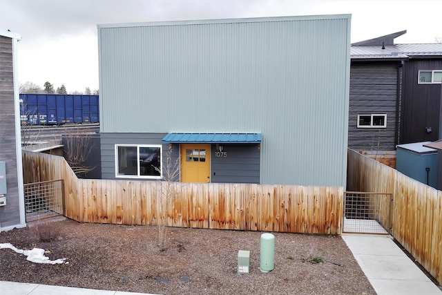 view of front of house with a gate, metal roof, and fence