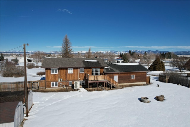 snow covered house featuring stairway, a mountain view, and fence