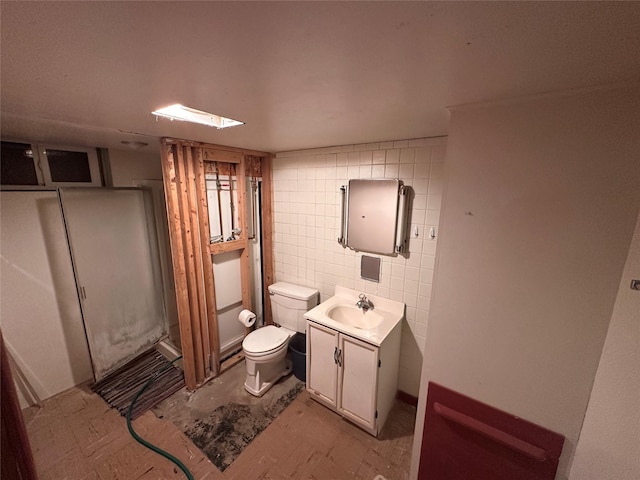 bathroom with vanity, tile walls, toilet, and a shower stall