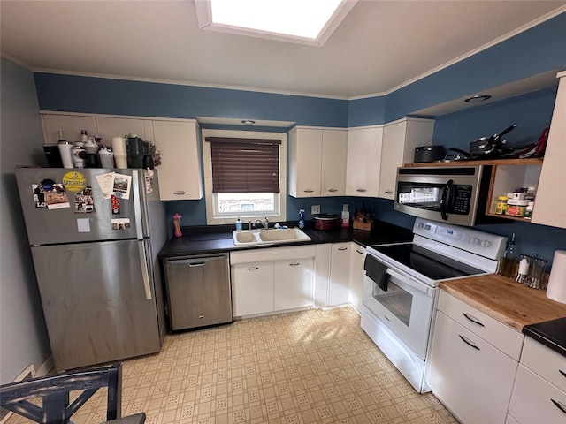 kitchen with a sink, dark countertops, white cabinetry, and stainless steel appliances