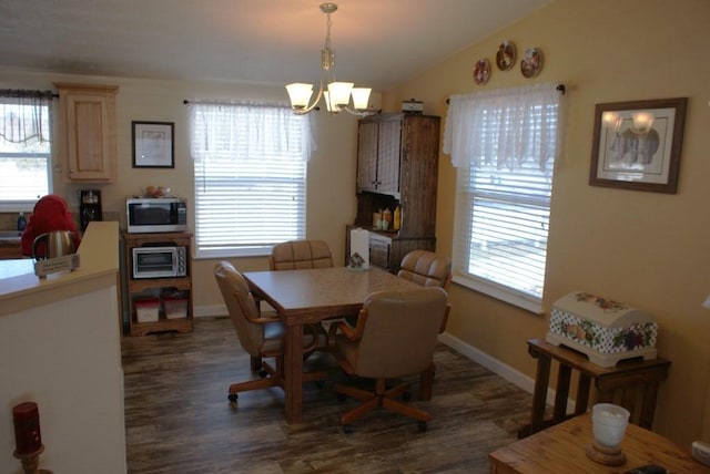 dining area with a notable chandelier, lofted ceiling, dark wood-type flooring, and baseboards