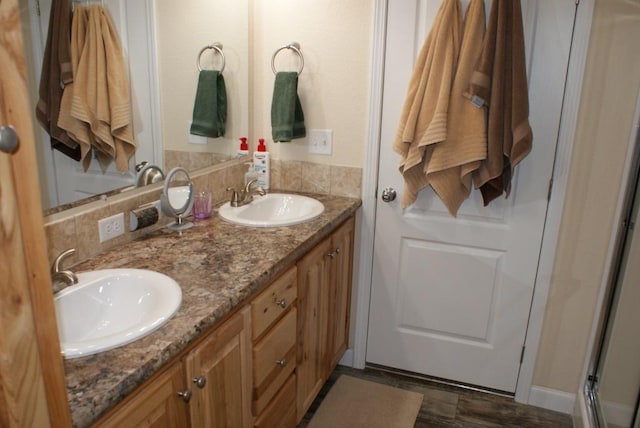 bathroom with double vanity, an enclosed shower, and a sink