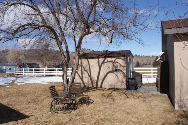 view of yard with an outbuilding, a storage unit, and fence