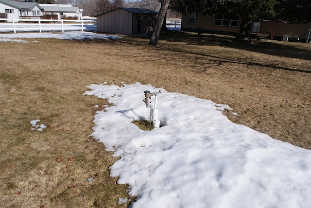 yard layered in snow with an outbuilding, a shed, and fence