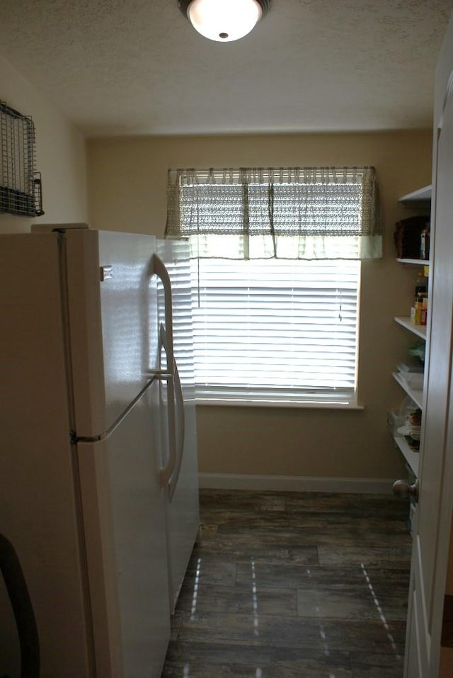 unfurnished dining area with baseboards, dark wood-type flooring, and a textured ceiling