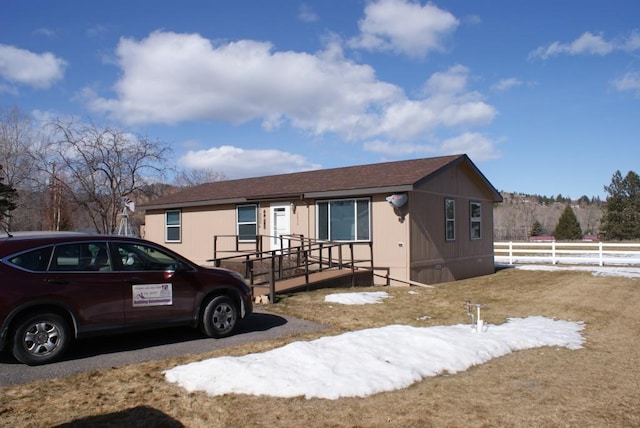 view of front of house featuring a shingled roof and fence