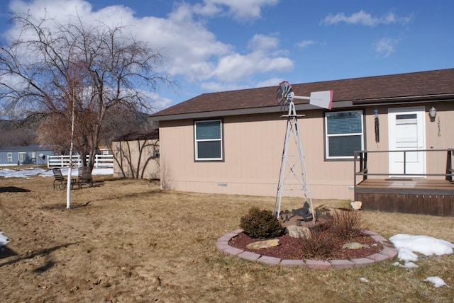 view of side of property with crawl space, a lawn, and a shingled roof