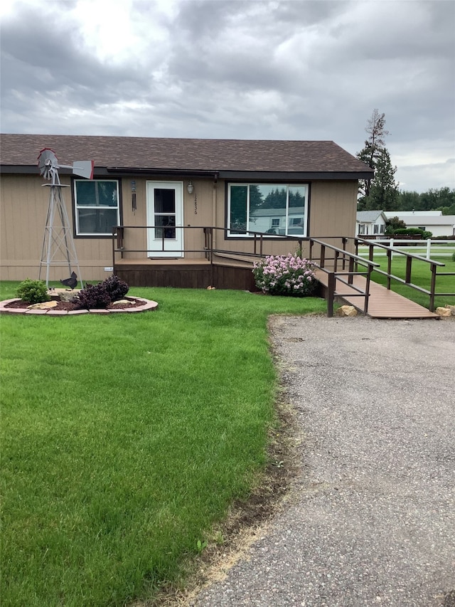 view of front of property featuring a shingled roof and a front lawn