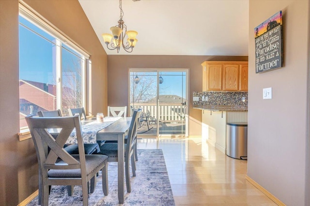 dining space featuring lofted ceiling, light wood-style flooring, a notable chandelier, and baseboards