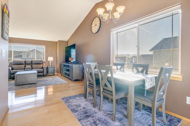 dining room with wood finished floors, baseboards, lofted ceiling, and a chandelier