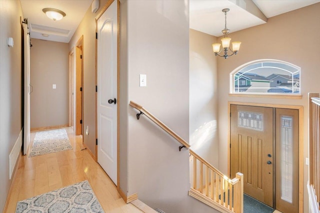 foyer entrance with an inviting chandelier, baseboards, and light wood-type flooring